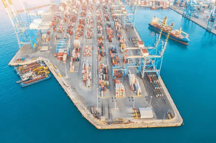 Aerial view of busy international shipping port with container vessels and cargo cranes